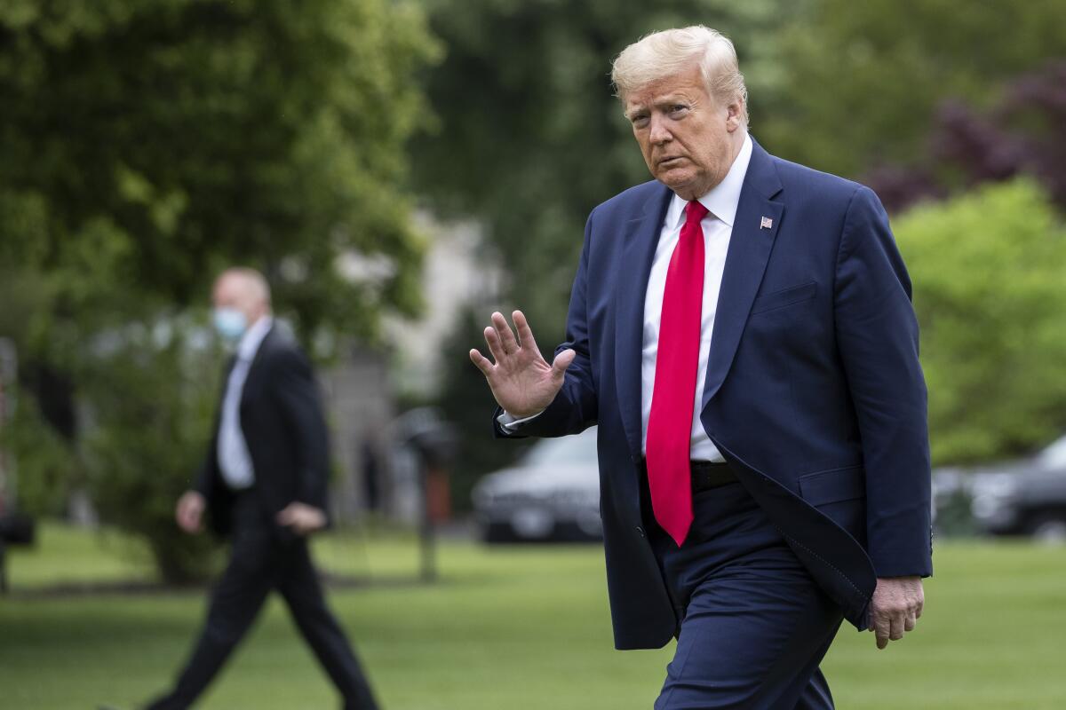 President Trump waves as he walks across the South Lawn of the White House on Sunday on his return from nearby Camp David, Md.