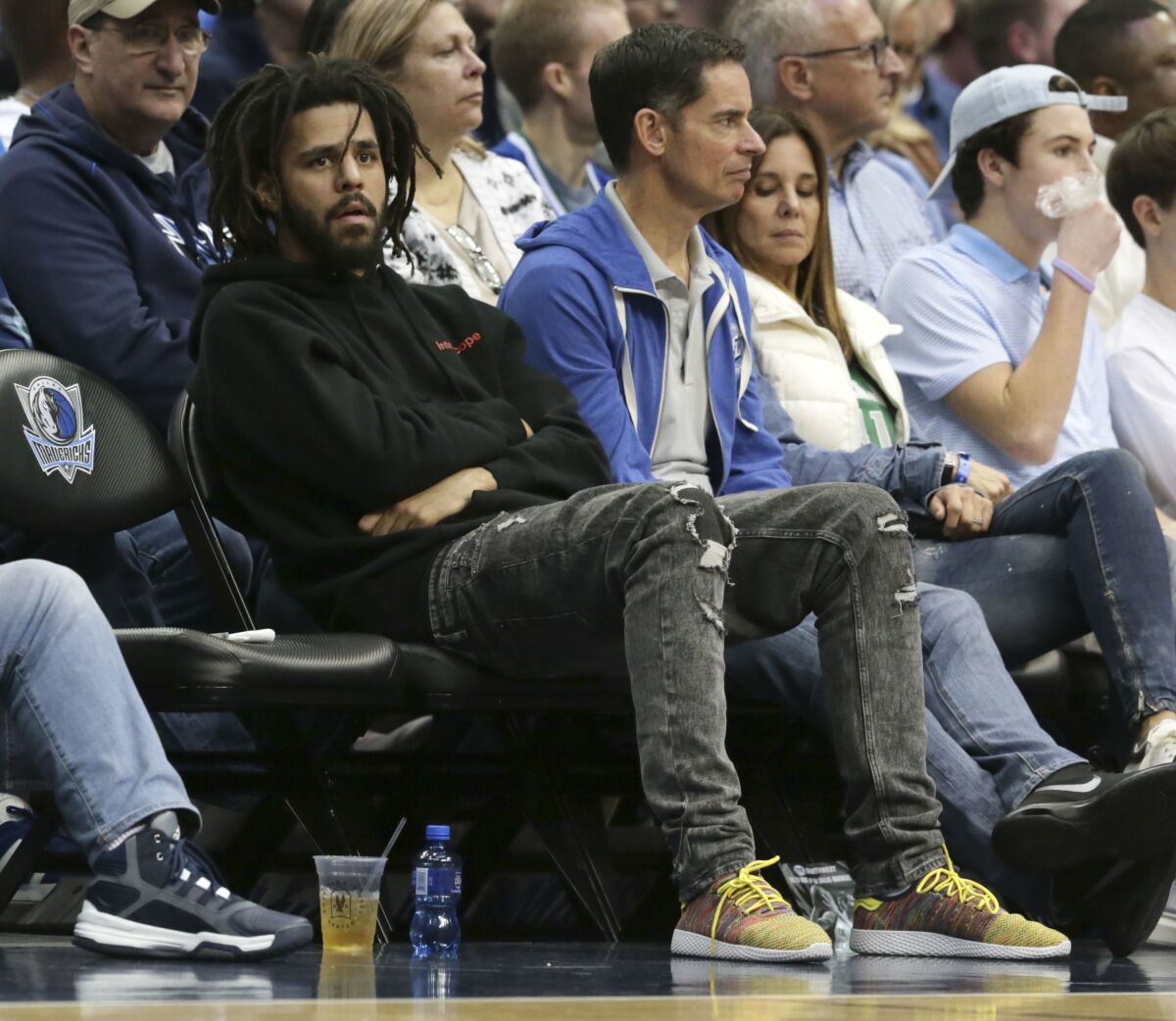 J. Cole sits courtside and watches an NBA basketball game between the Detroit Pistons and Dallas Mavericks in Dallas.