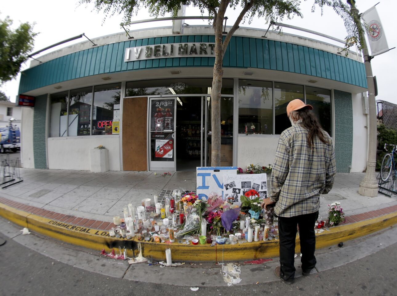 A passerby pays his respects at a makeshift memorial in front of the IV Deli Mart.