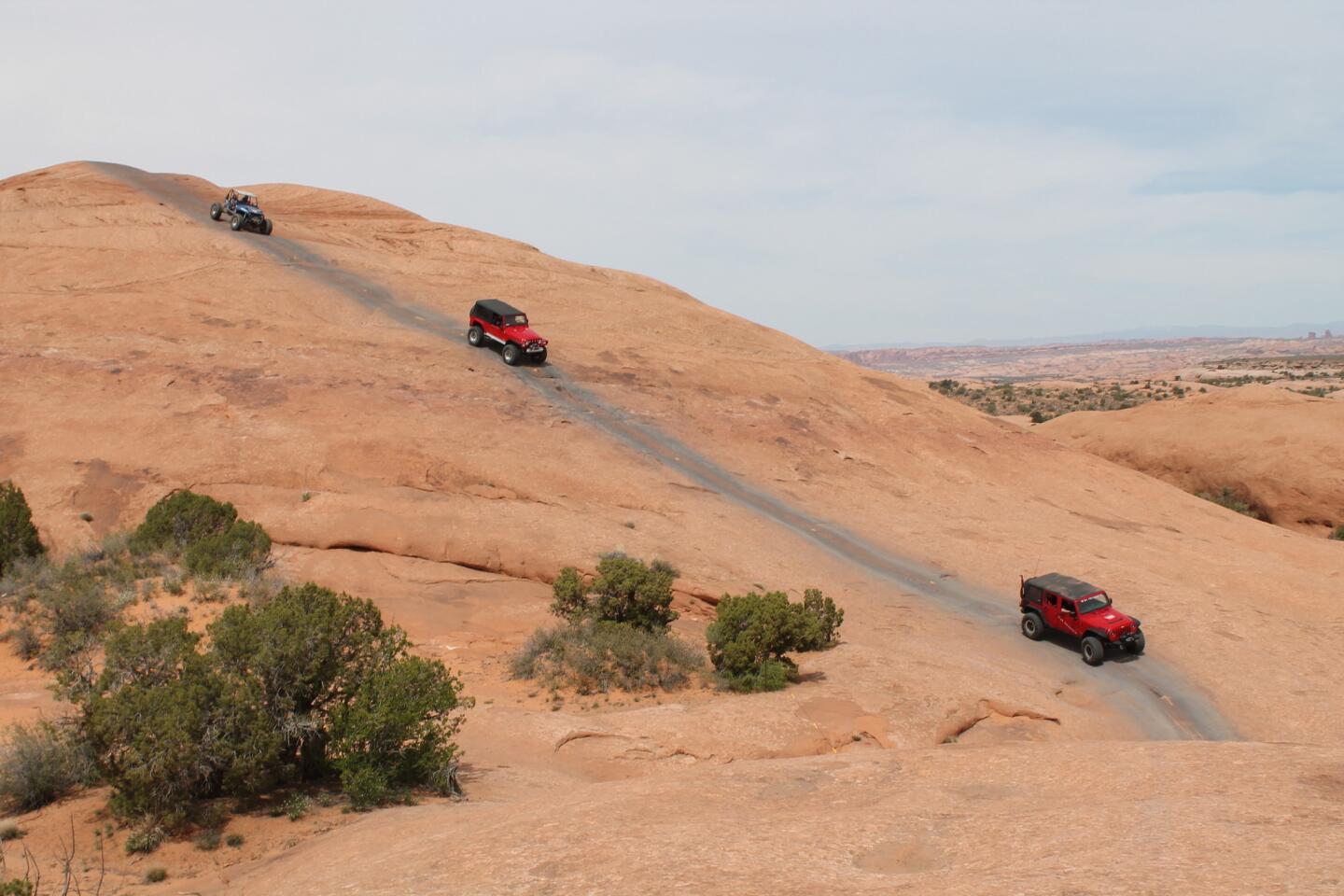 A trio of Jeeps descends a portion of Hell's Revenge Trail outside Moab, Utah, as part of the Easter Jeep Safari.