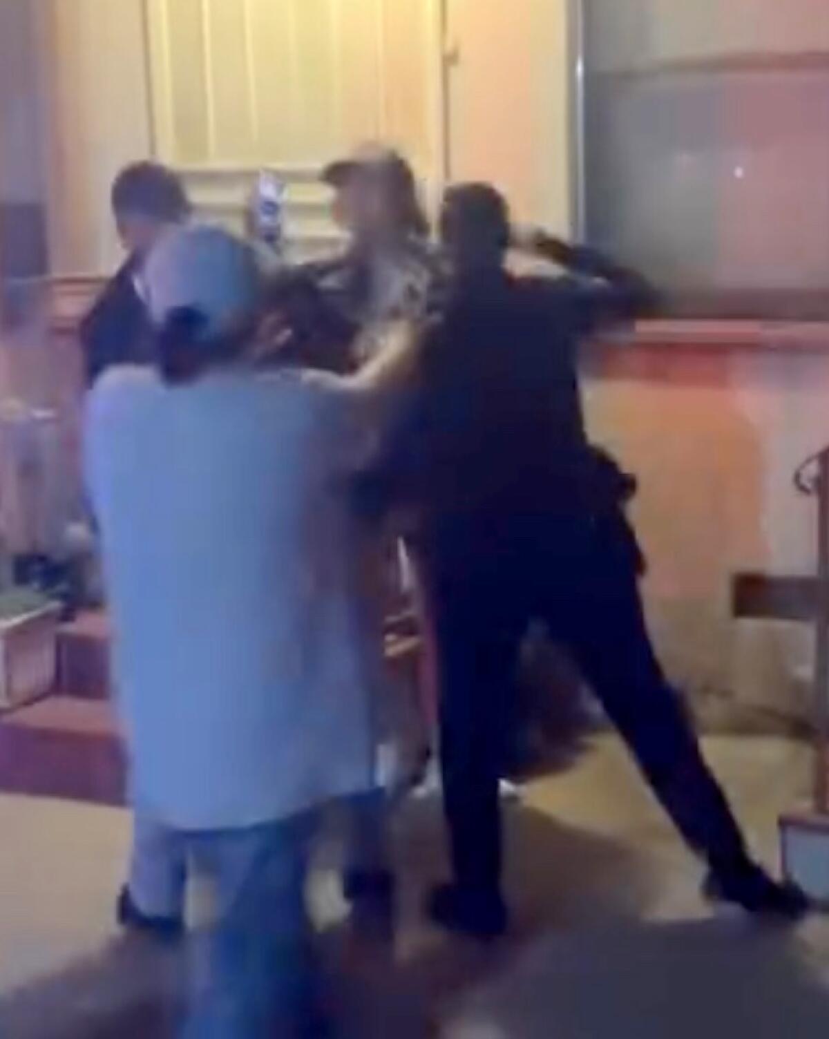 An image from video shows a police officer with a fist raised toward a person's face.