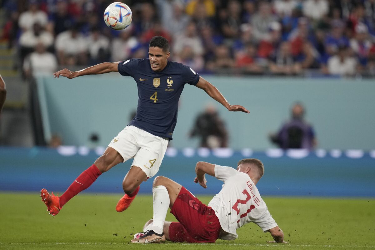 France's Raphael Varane, left, challenges for the ball with Denmark's Andreas Cornelius during the World Cup group D soccer match between France and Denmark, at the Stadium 974 in Doha, Qatar, Saturday, Nov. 26, 2022. (AP Photo/Christophe Ena)