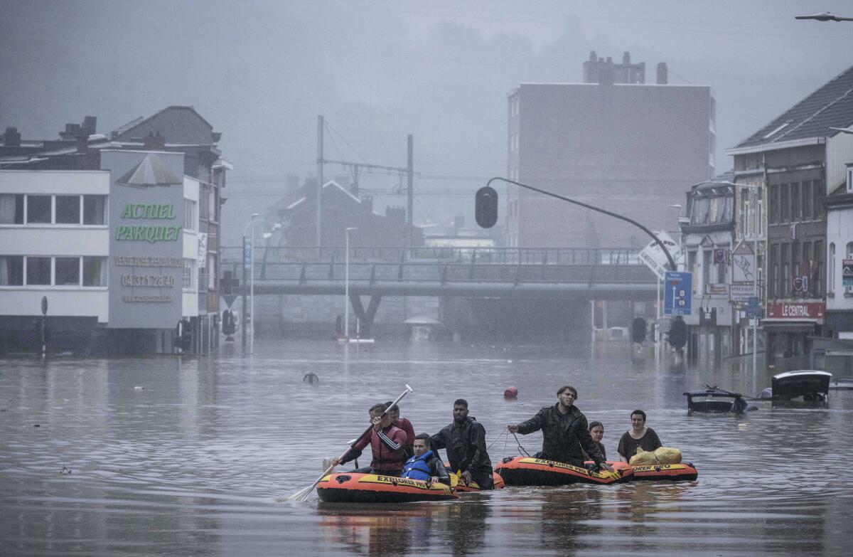 People use rubber rafts during heavy flooding to float down a street with buildings on it