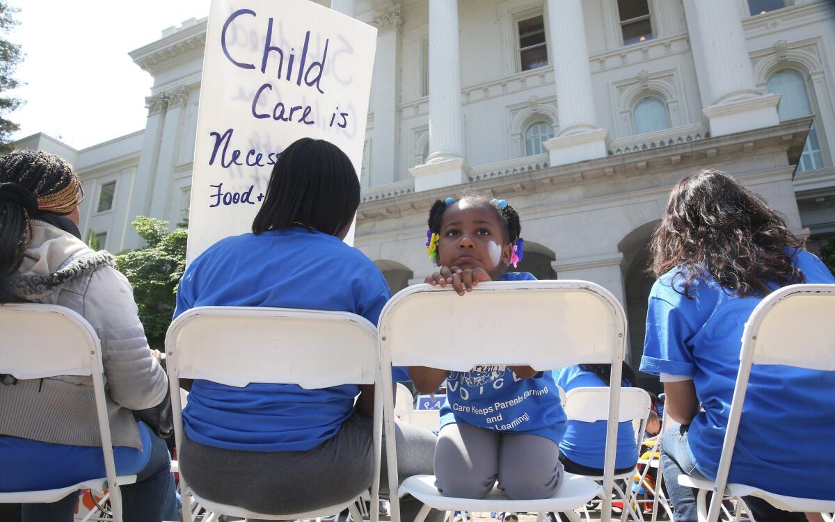 A young girl sits with her mother at a rally calling for increased child care subsidies at the Capitol in Sacramento on May 6.