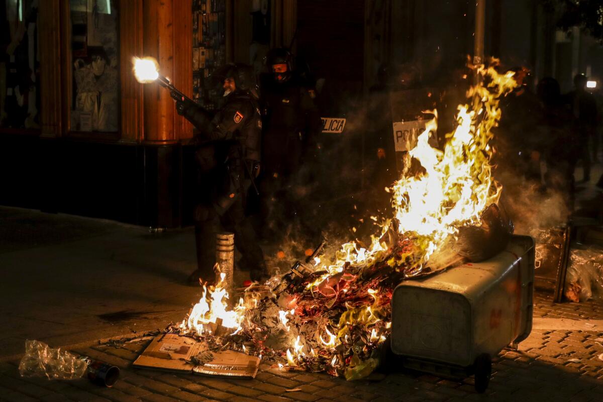 A police officer opens fire near a trash can set ablaze in Madrid