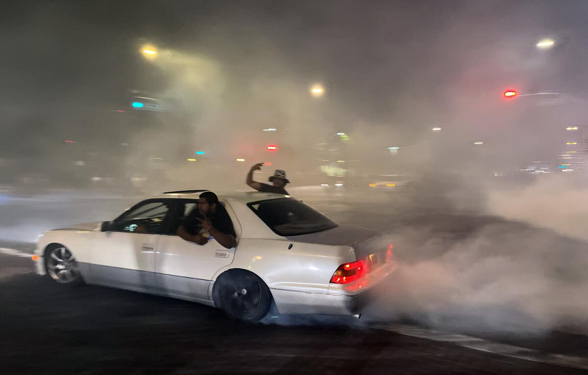 A car on a road with smoke coming off its rear tires.