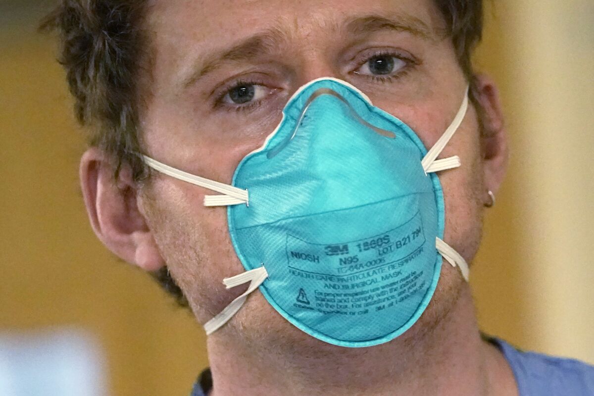Registered nurse Scott McGieson wears an N95 mask as he walks out of a patient's room in the acute care unit of Harborview Medical Center, Friday, Jan. 14, 2022, in Seattle. Washington Gov. Jay Inslee is deploying 100 members of the state National Guard to hospitals across the state amid staff shortages due to an omicron-fueled spike in COVID-19 hospitalizations. Inslee announced Thursday that teams will be deployed to assist four overcrowded emergency departments at hospitals in Everett, Yakima, Wenatchee and Spokane, and that testing teams will be based at hospitals in Olympia, Richland, Seattle and Tacoma. (AP Photo/Elaine Thompson)