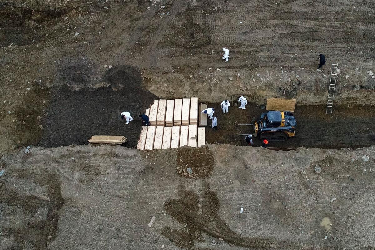 Workers wearing personal protective equipment bury bodies in a trench on Hart Island, New York City’s longtime potter’s field, last month.