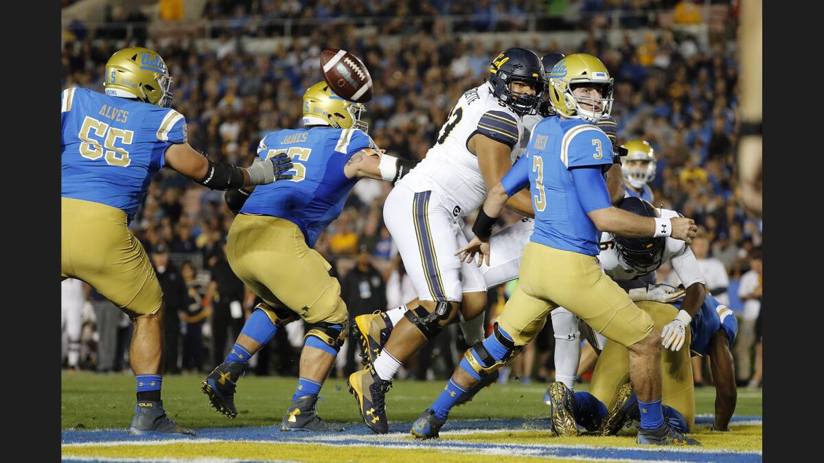 UCLA quarterback Josh Rosen fumbles the ball in the end zone under pressure by California defensive lineman Luc Bequette (93) and linebacker Raymond Davison III (31) during the first half.