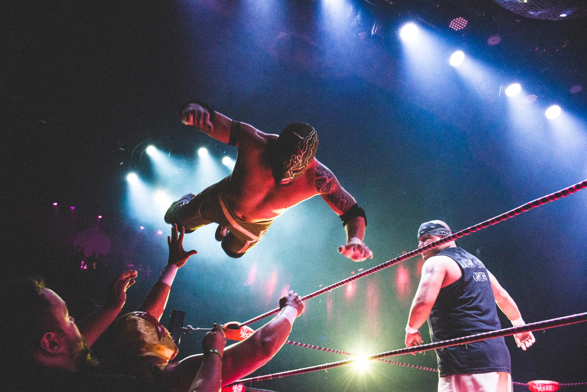 A masked Mexican wrestler flies from the ring at a Lucha VaVoom show.