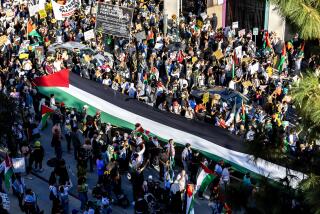 LOS ANGELES, CA - OCTOBER 28, 2023: A large Palestinian flag is carried as thousands of demonstrators march through the downtown streets to protest the death toll inflicted on the Palestinians during the Israel-Hamas war in Gaza on October 28, 2023 in Los Angeles, California.(Gina Ferazzi / Los Angeles Times)