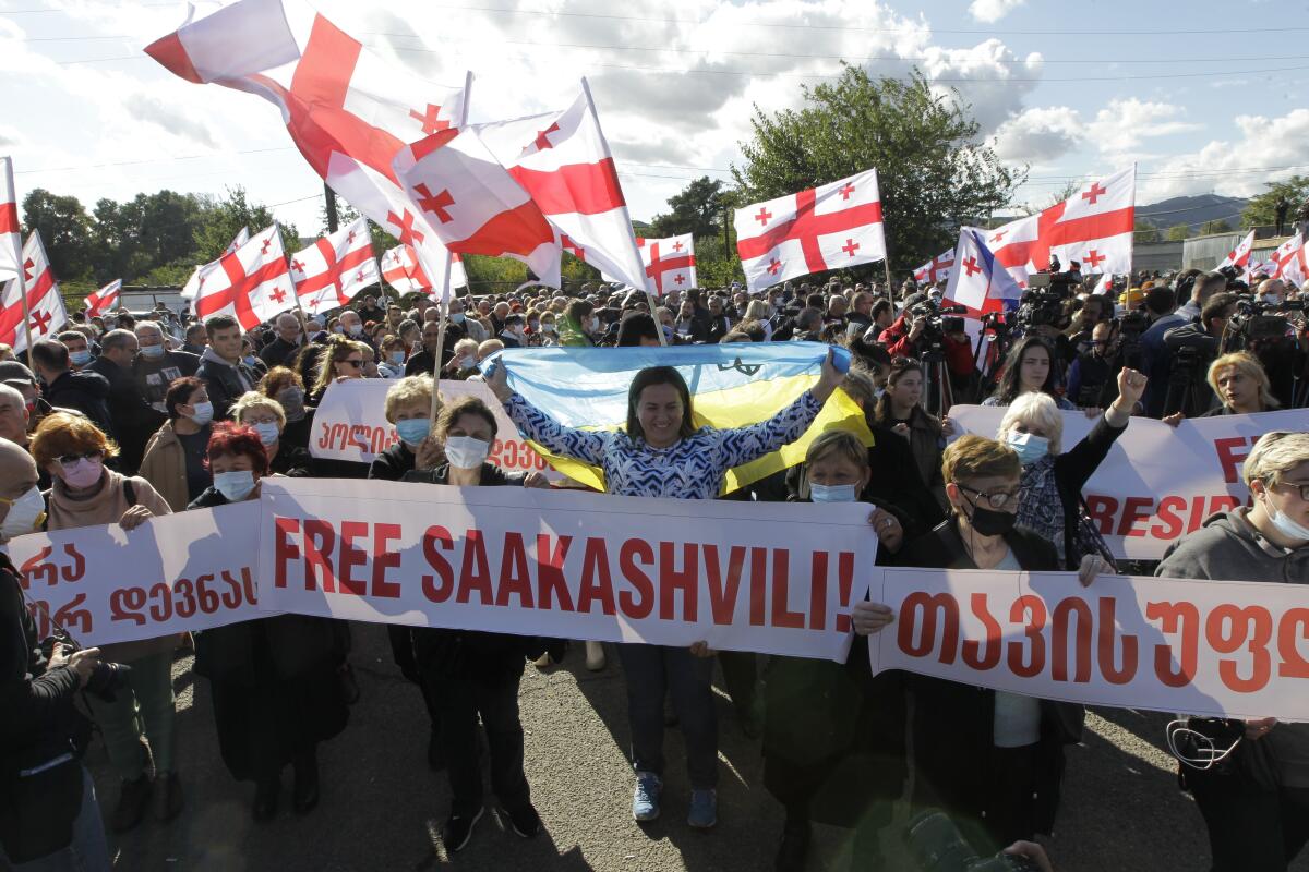 Georgian opposition supporters of former president Mikheil Saakashvili hold Georgian and Ukrainian national flags during a rally in his support in front of the prison where former president is being held, in Rustavi, about 20 km from the capital Tbilisi, Georgia, Monday, Oct. 4, 2021. Saakashvili was detained in Tbilisi on Saturday, Oct. 1, 2021. Georgia earlier declared Saakashvili wanted as a person convicted in absentia in several criminal cases and treated as a suspect in some others. Georgian authorities have warned repeatedly that he would be detained immediately once over the border. (AP Photo/Shakh Aivazov)