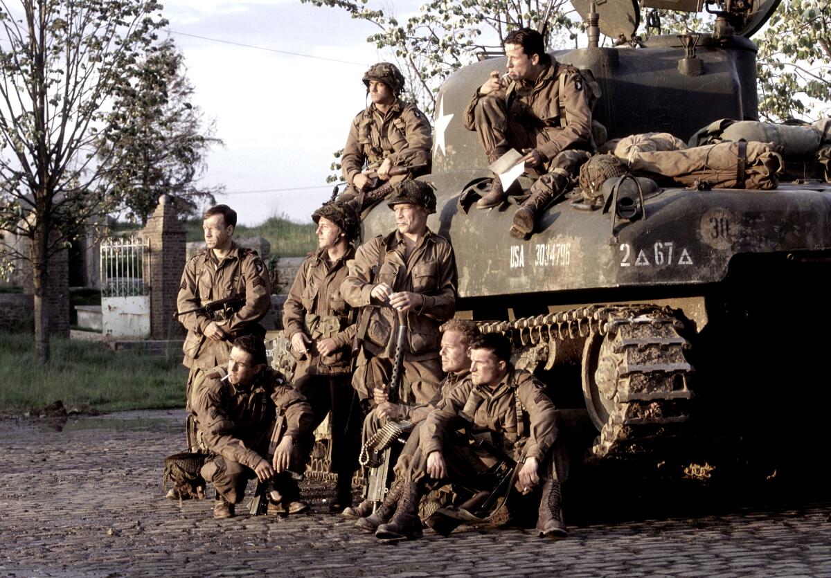 WWII soldiers pose around a tank.