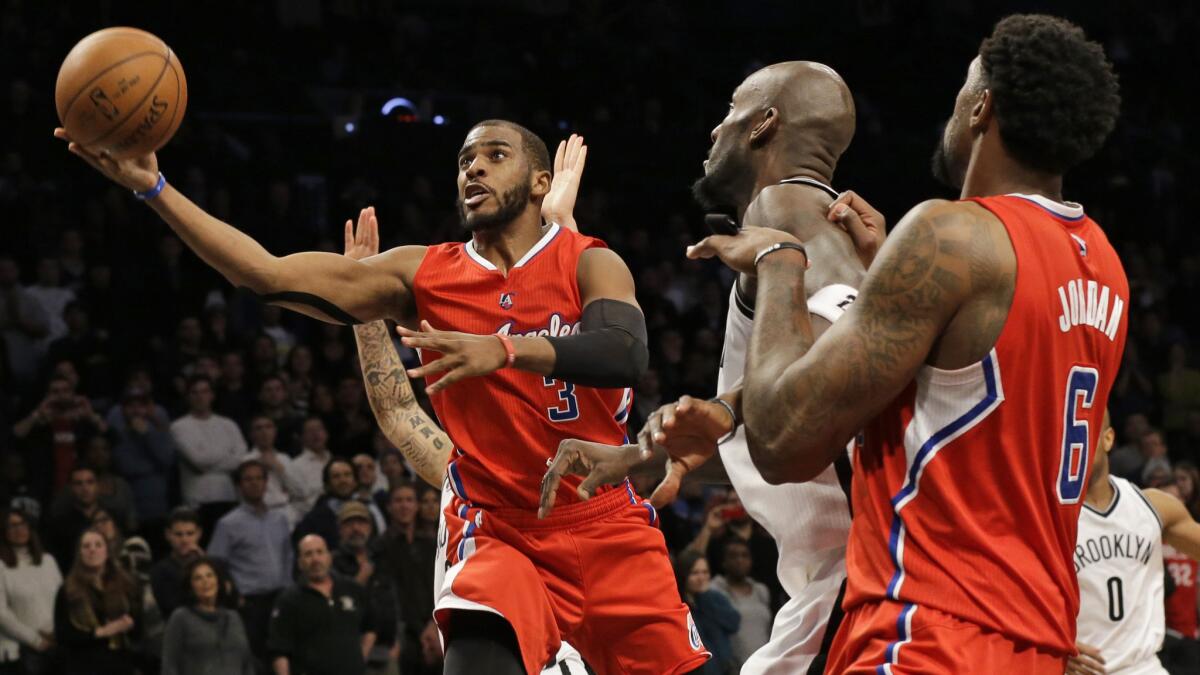 Clippers point guard Chris Paul, left, puts up a shot in front of Brooklyn Nets forward Kevin Garnett, center, and Clippers center DeAndre Jordan during the Clippers' 102-100 loss Monday.