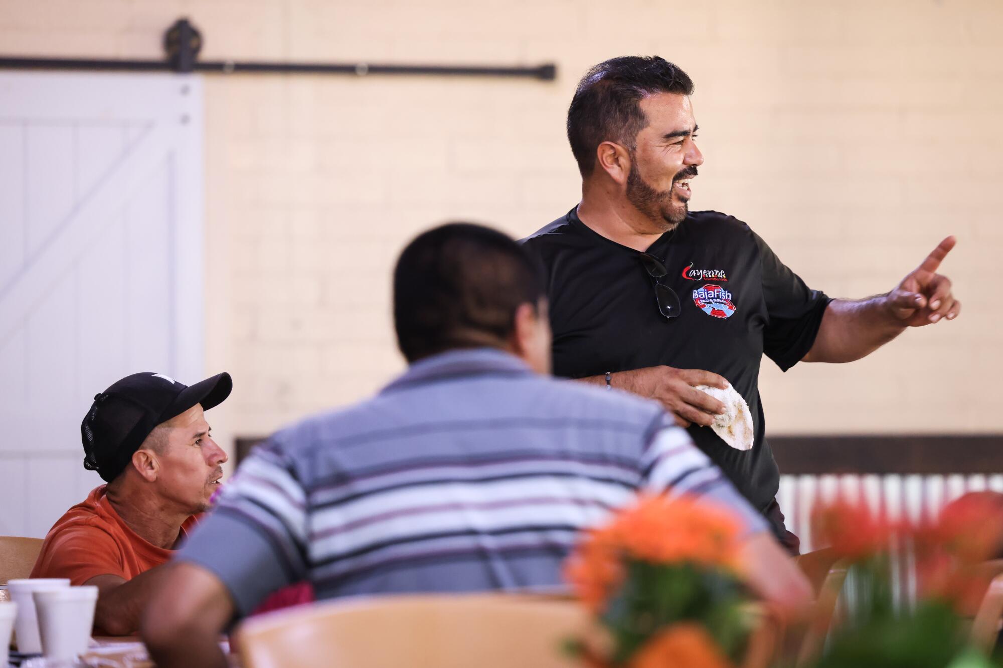 Omar Vergara, owner of Grupo Cayenne, right, chats with workers in during a break from passing out meals.