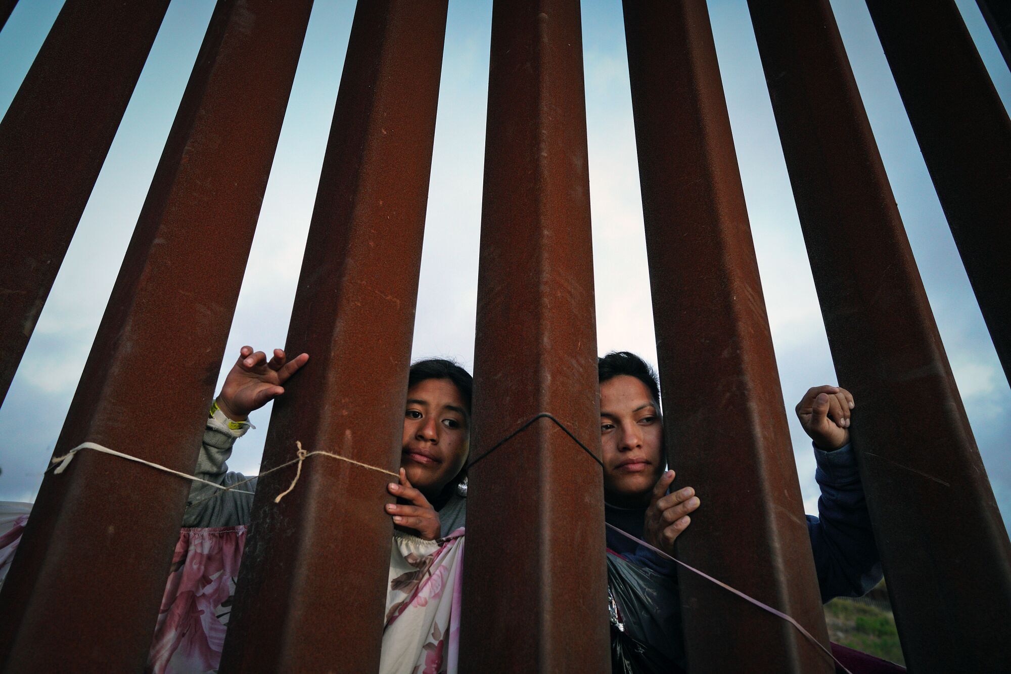 Migrants peer through the border fence at Dairy Mart Rd. in San Diego, CA on Thursday, May 11, 2023