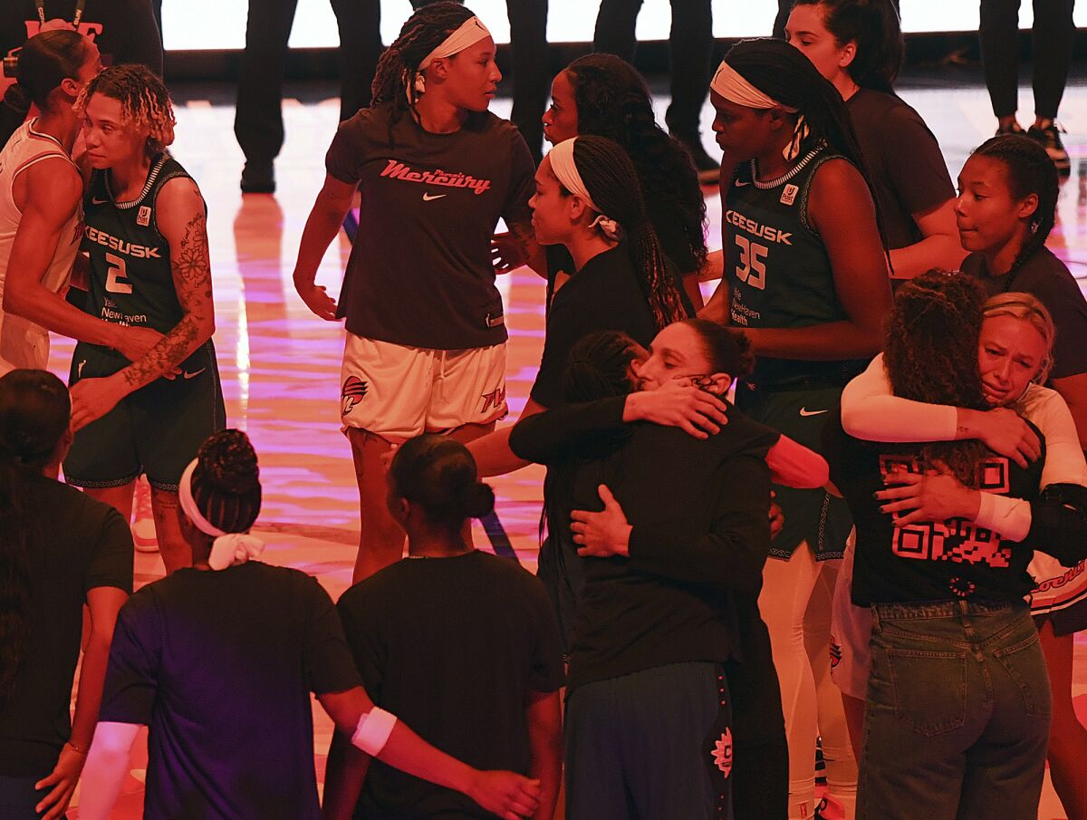 Players with the Connecticut Sun and Phoenix Mercury embrace following a moment of silence for Phoenix Mercury center Brittney Griner before a WNBA basketball game Thursday, Aug. 4, 2022, in Uncasville, Conn. Griner was convicted Thursday in Russia of drug possession and smuggling and was sentenced to nine years behind bars. (Sarah Gordon/The Day via AP)
