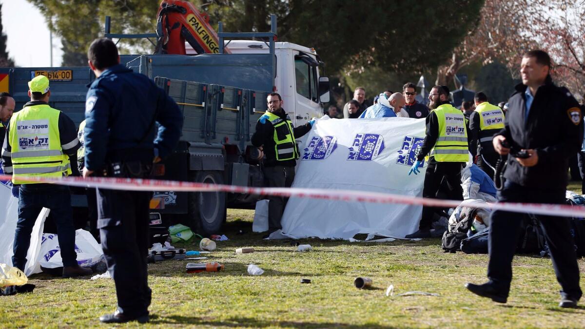 Israeli security forces stand guard as medics cover bodies at the site of the truck ramming in Jerusalem.