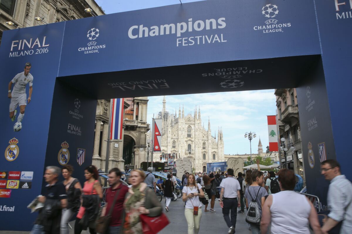 FILE - People walk by the Uefa Champions League fans zone near the Duomo gothic cathedral, in Milan, Italy, on May 25, 2016. Champions League organizer UEFA is being criticized by supporter groups for monetizing engagement by partnering with a company that sells fan tokens through largely unregulated cryptocurrencies. The commercial deal was announced a day after the Football Supporters Europe group praised UEFA for giving away 10,000 tickets to the Champions League final this season, with thousands of fans also able to attend the other European club competition finals for free. (AP Photo/Luca Bruno)
