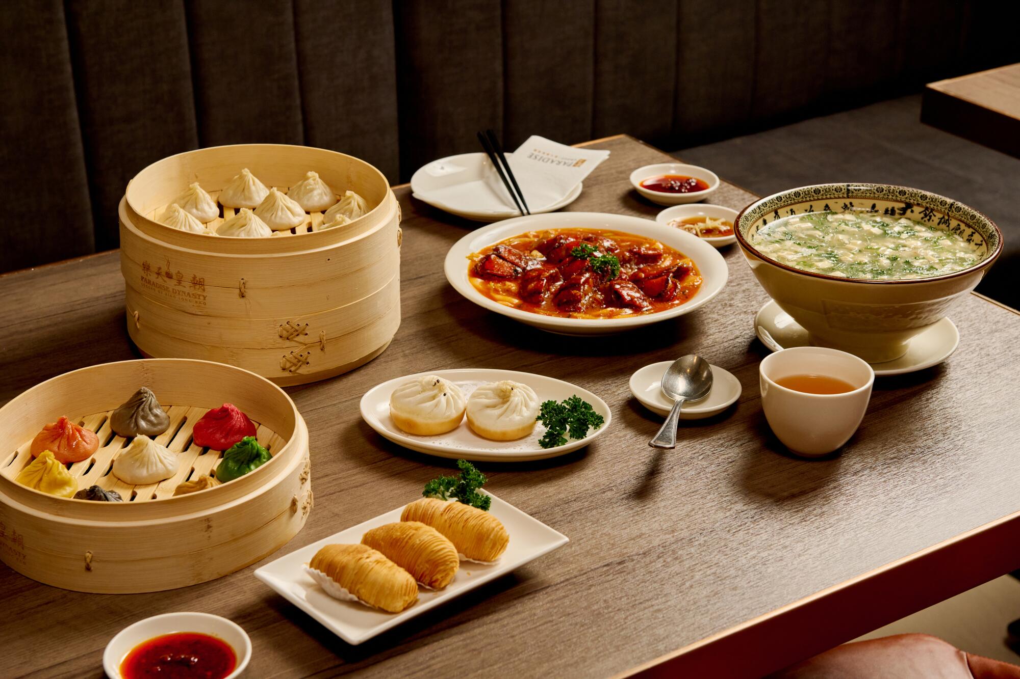 Steamer baskets, plates and bowls full of food on a table, seen from the diner's perspective.