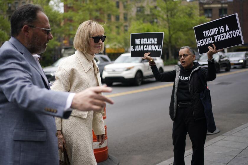 While a protester holds up signs, E. Jean Carroll arrives to federal court in New York, Thursday, April 27, 2023. Carroll began testifying Wednesday in the trial of her federal lawsuit. The writer has told a jury that Donald Trump raped her after she accompanied him into a luxury department store fitting room in 1996. (AP Photo/Seth Wenig)