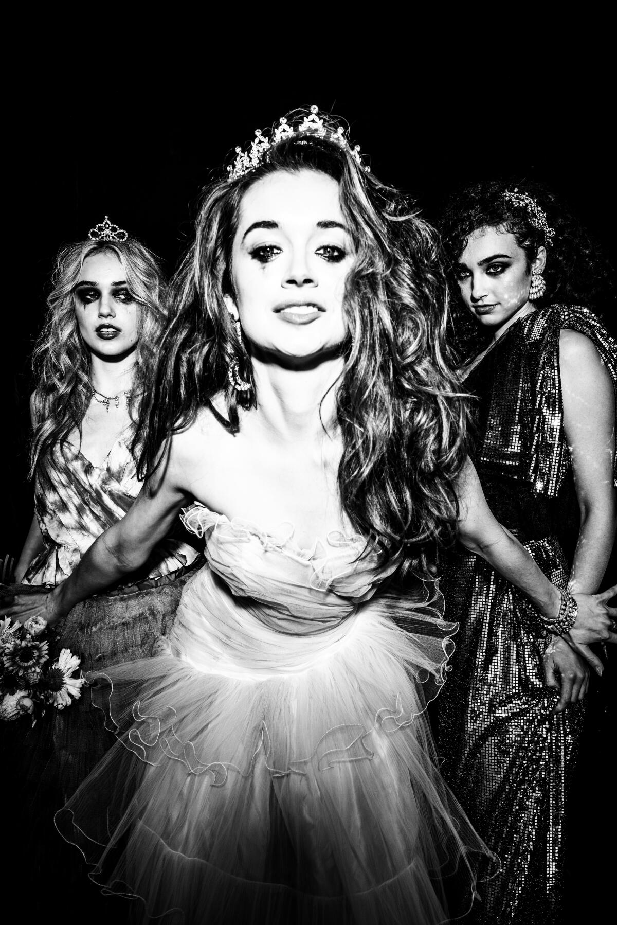 Three women wearing gowns and crowns with smeared eye makeup.