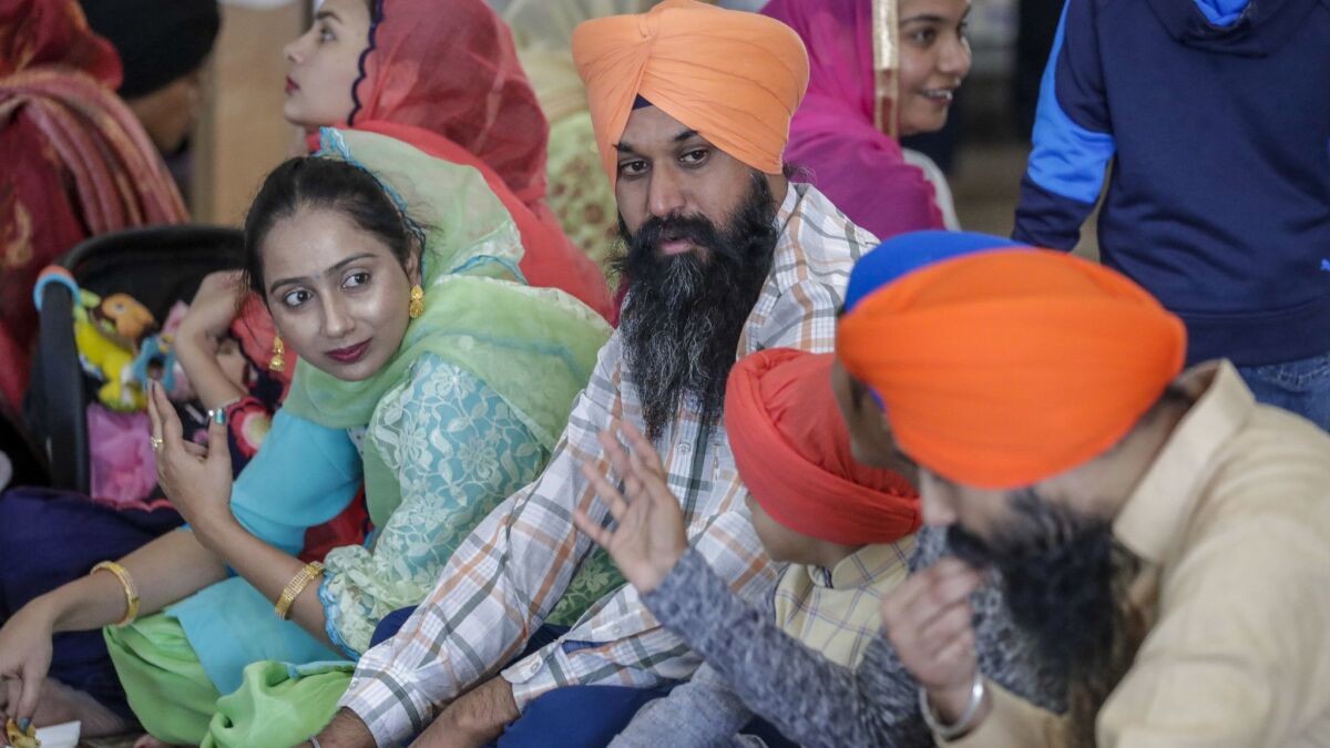 Palwinder Singh, 38, center, with his wife, Harjeet Kaur, left, eat with their 4-year-old son and other relatives at the Riverside Gurdwara in Jurupa Valley.