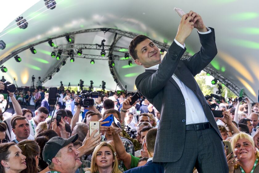 A man in a suit takes a selfie in front of a crowd
