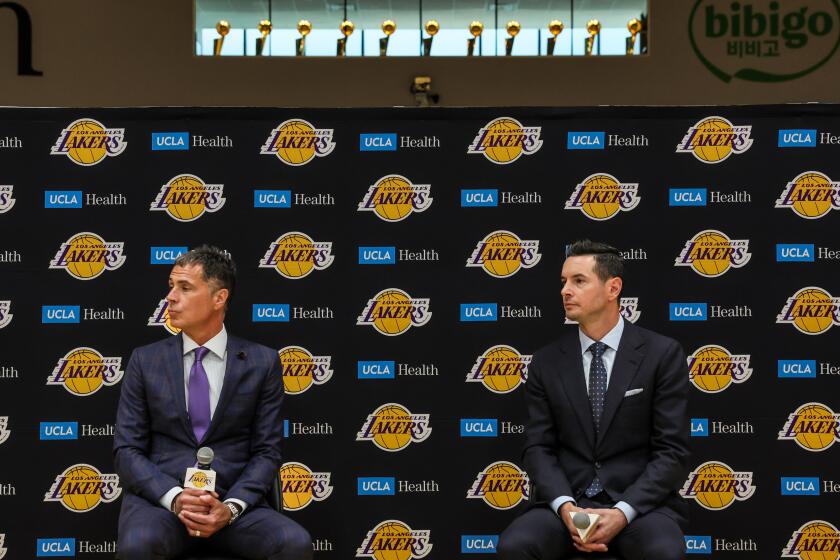 Lakers general manager Rob Pelinka sits on a stool and introduces JJ Redick as the team's head coach
