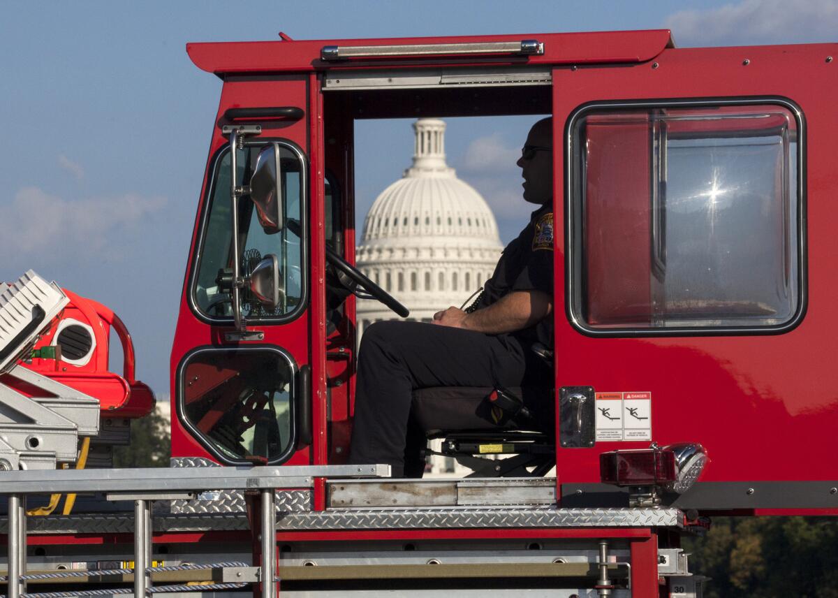 A firefighter sits in a fire truck near the scene on the National Mall in Washington, where, according to a fire official, a man set himself on fire Friday, Oct. 4, 2013. The official said the man was flown by helicopter to a hospital.