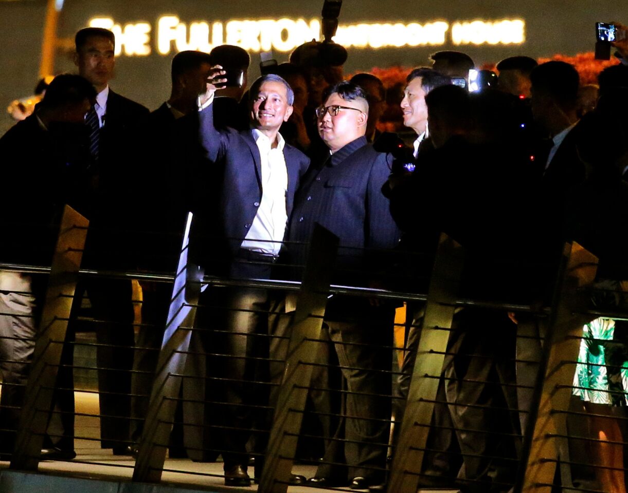North Korean leader Kim Jong-un, center and Singapore Foreign Minister Vivian Balakrishnan take selfies on the Jubilee bridge at the Esplanade in Singapore.