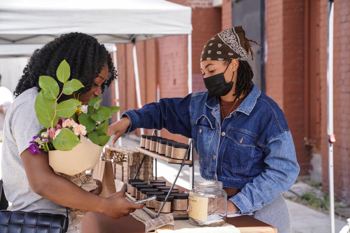 Someone holding a bouquet makes a purchase at the Prosperity Market