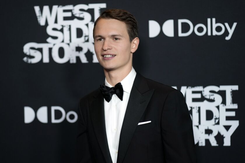 A young man in a tuxedo poses at a film premiere