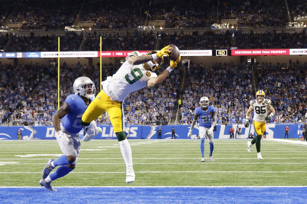 Packers wide receiver Christian Watson (9) makes a touchdown catch as other players run toward him.