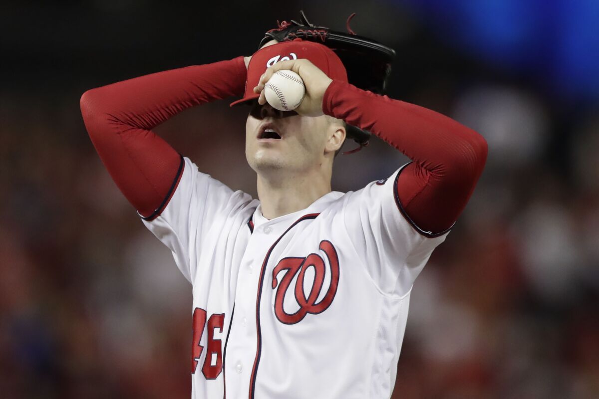 Washington Nationals starting pitcher Patrick Corbin covers his face after allowing a two-run double to Los Angeles Dodgers Russell Martin during the sixth inning in Game 3 of a baseball National League Division Series.