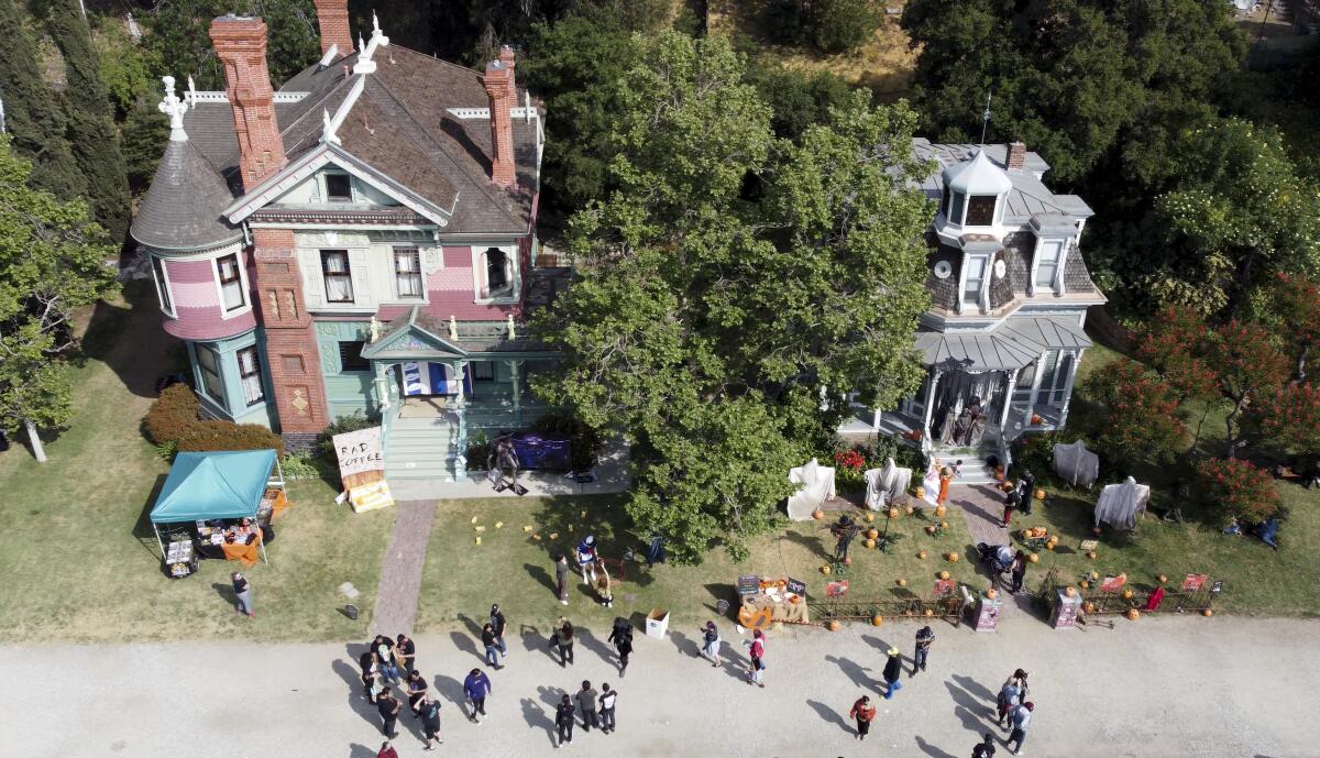 An aerial view of large Victorian houses with people in front.