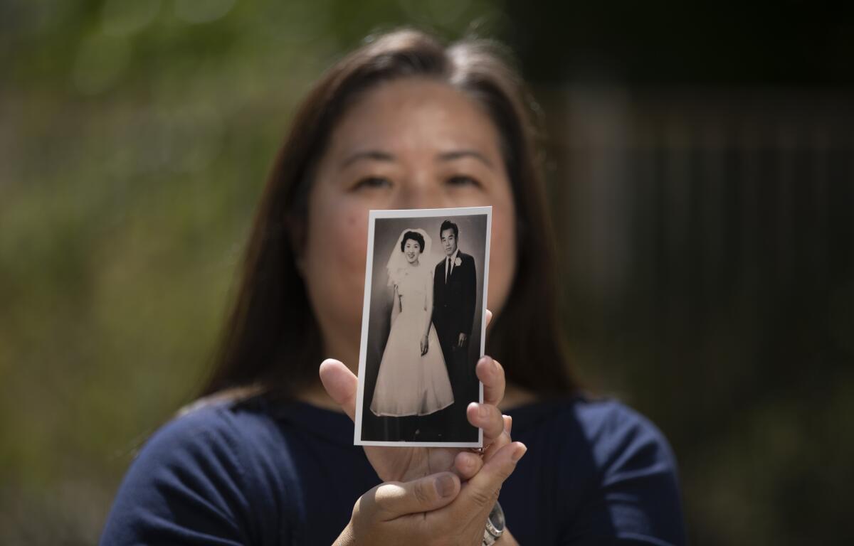 A woman holds up a back-and-white picture of a bride and groom.