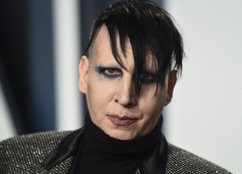 A man with dark hair wearing eye makeup and lipstick.
