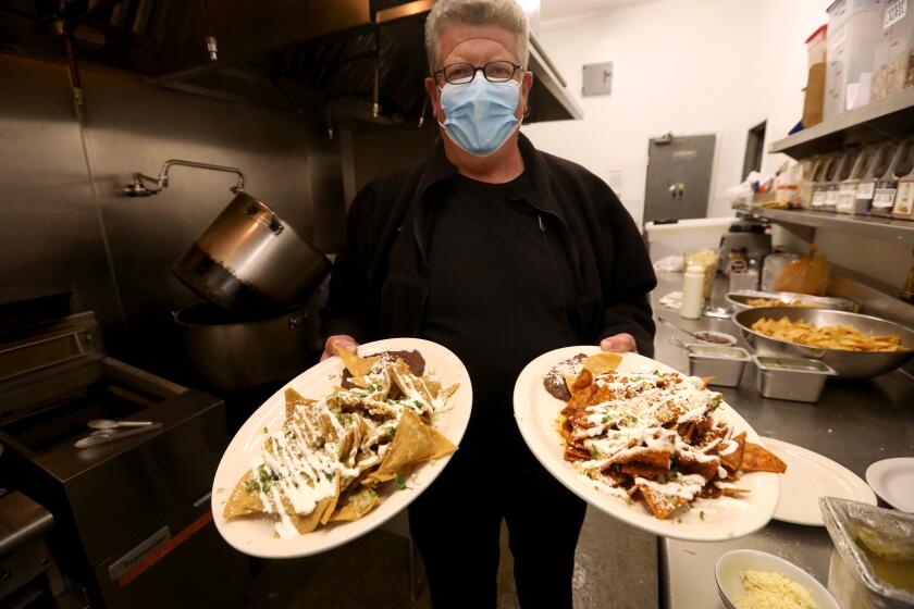 LOS ANGELES, CA - DECEMBER 10, 2021 - Chef Jimmy Shaw holds two plates of chilaquiles to be sampled by Los Angeles Times Columnist Steve Lopez in the kitchen of Shaw's place Loteria Grill in Los Angeles on December 10, 2021. (Genaro Molina / Los Angeles Times)