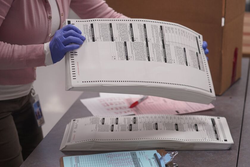 Una trabajadora electoral recoge papeletas tabuladas para ser almacenadas dentro de la Oficina de Registros del Condado de Maricopa, el jueves 10 de noviembre de 2022, en Phoenix. (AP Foto/Matt York)