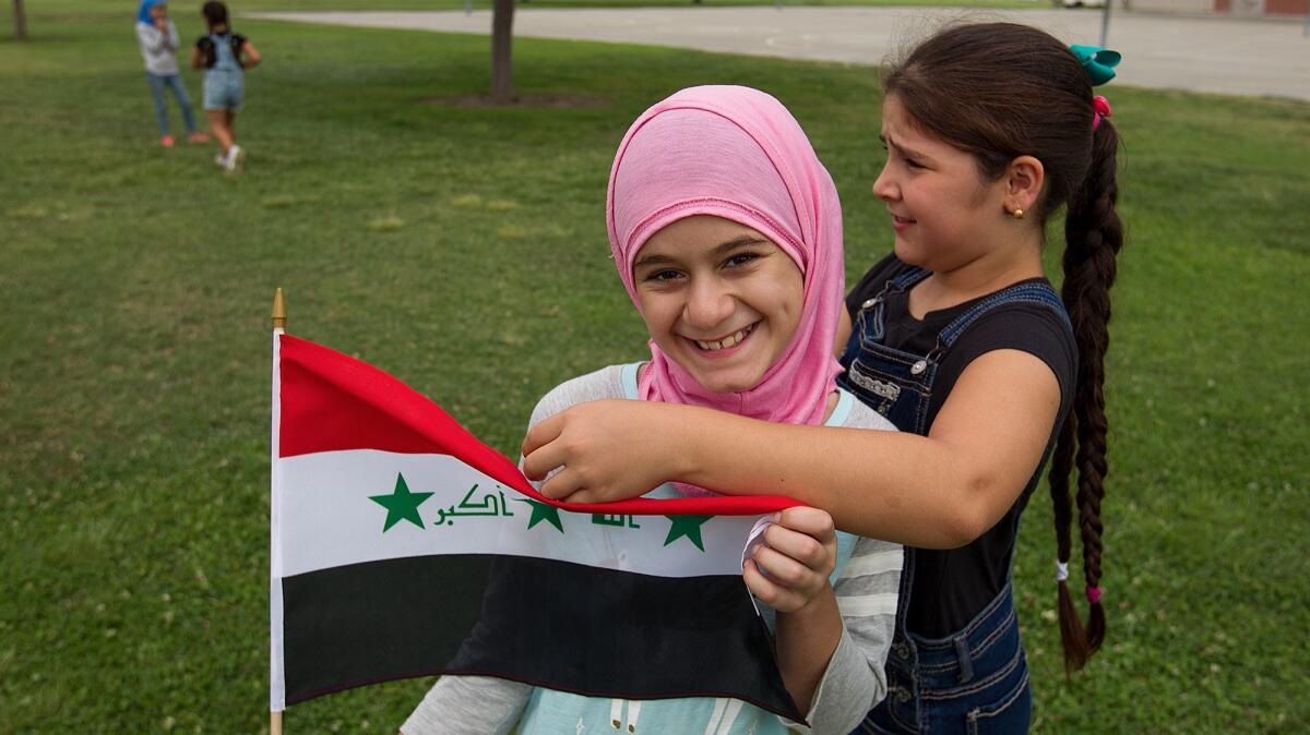 Zainab Zabiba, 11, left, and Rafal Albayati, 10, play while holding an Iraqi flag on Aug. 23 at World Cup Summer Soccer Camp in Westminster.