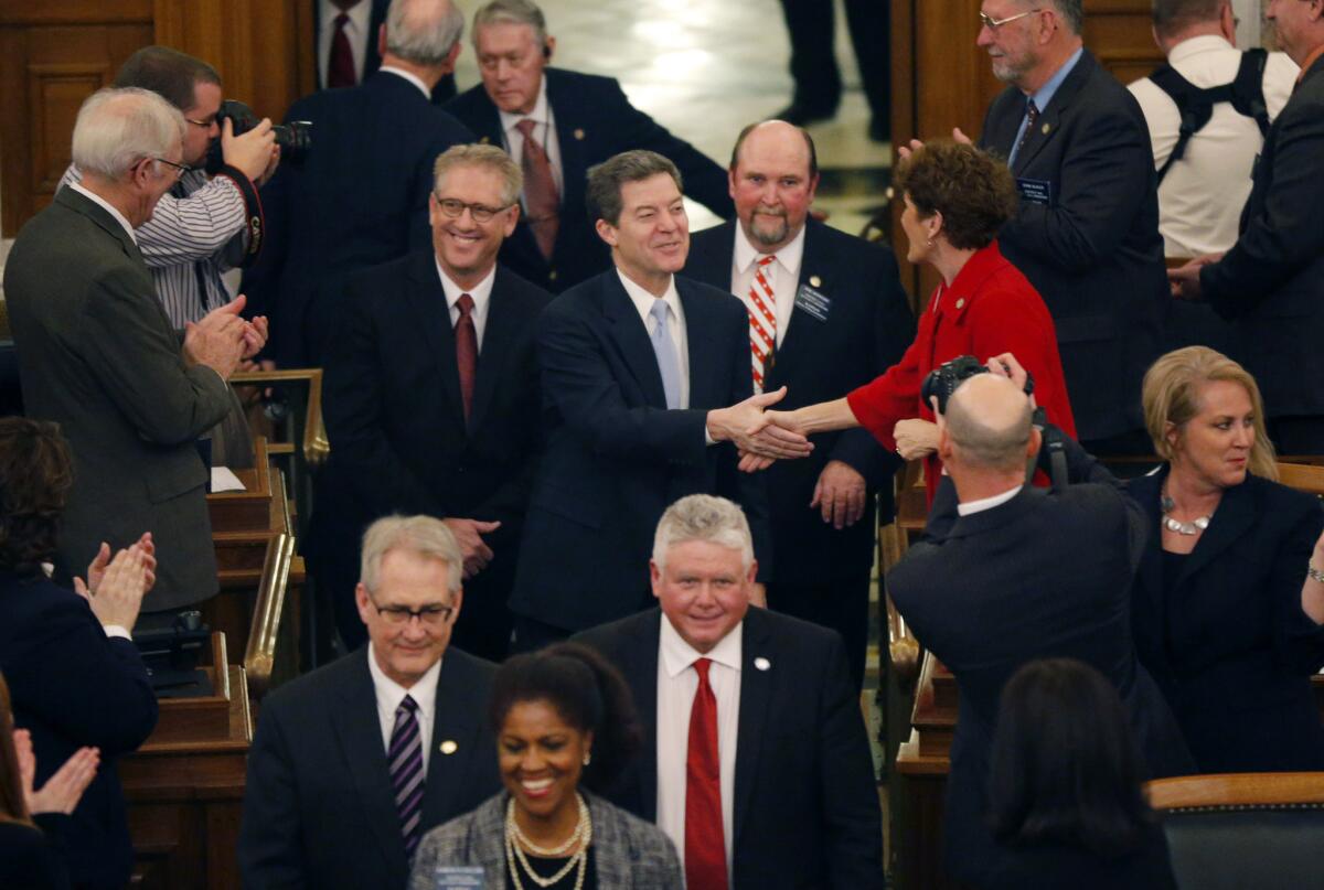 Kansas Gov. Sam Brownback greets representatives before his State of the State speech to an annual joint session of the House and Senate at the Statehouse in Topeka, Kan. Brownback told Kansas legislators that the tax cuts he championed will spur economic growth.