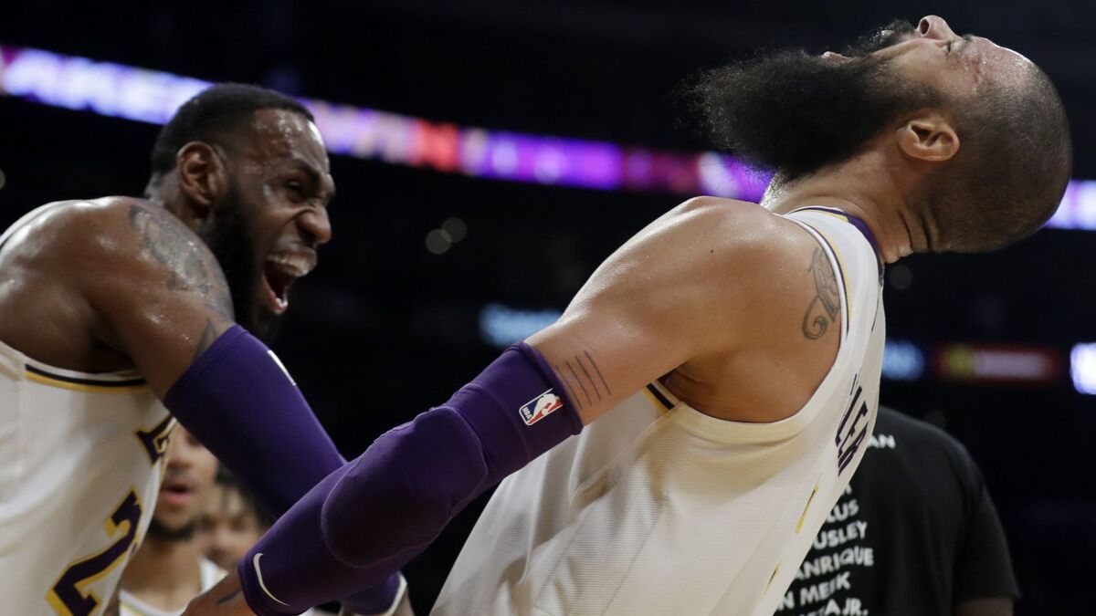 Lakes center Tyson Chandler, right, celebrates with teammate LeBron James after blocking a last-season shot by Hawks guard Trae Young on Sunday.