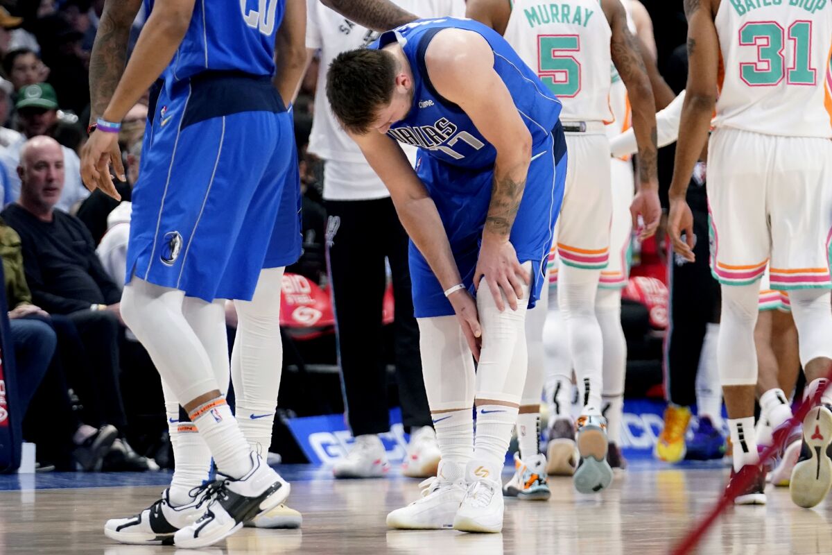 Dallas Mavericks' Luka Doncic (77) reaches for his lower leg after suffering an unknown lower leg injury in the second half of an NBA basketball game against the San Antonio Spurs, Sunday, April 10, 2022, in Dallas. (AP Photo/Tony Gutierrez)