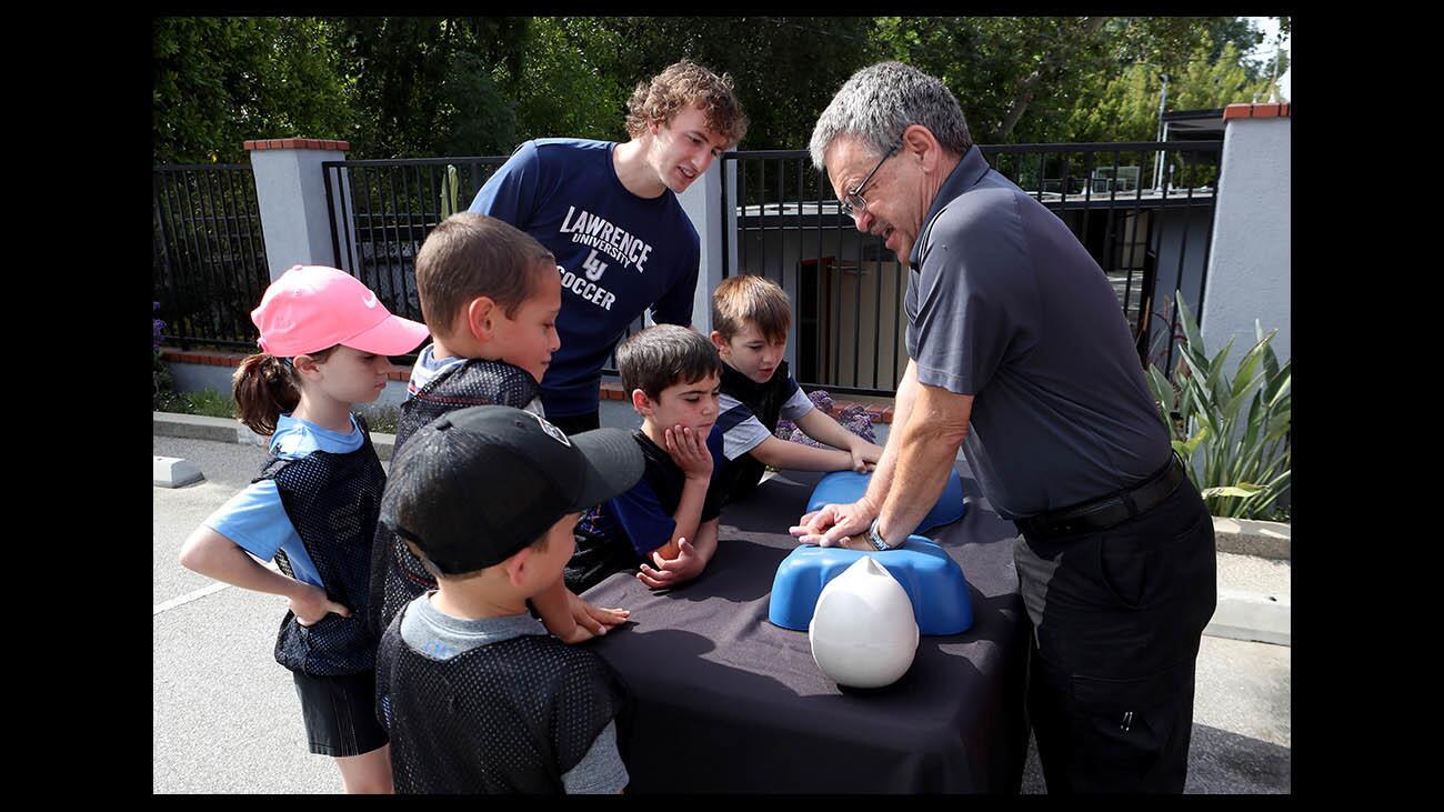 Ambulnz EMS director Lucian Badica, right, shows local children how CPR is performed, at the Verdugo Hills Hospital Sidewalk CPR event, at the Community Center of La Canada Flintridge, on Thursday, June 7, 2018.