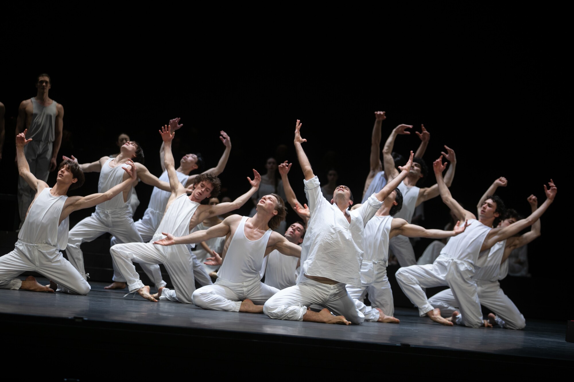 A line of male dancers raises arms heavenward.