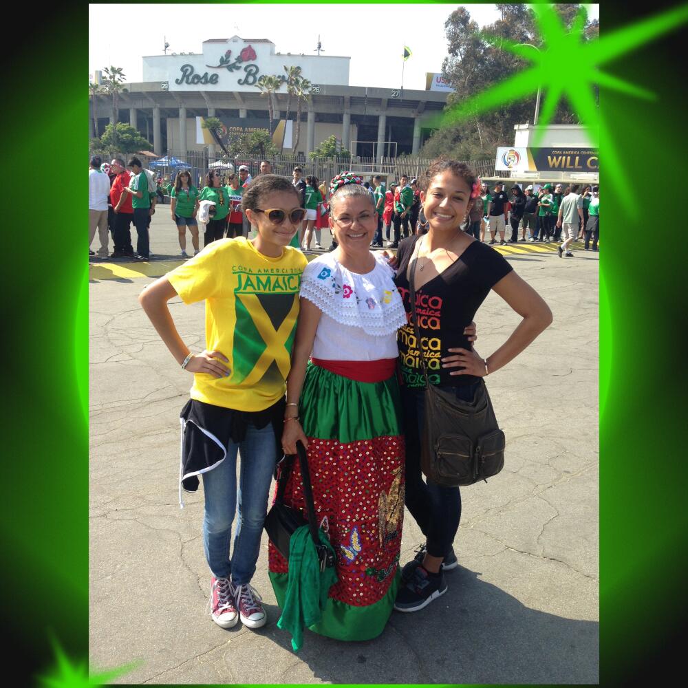 A woman in Jamaica gear, a woman in a Mexican skirt and blouse, and a woman in black outside the Rose Bowl.