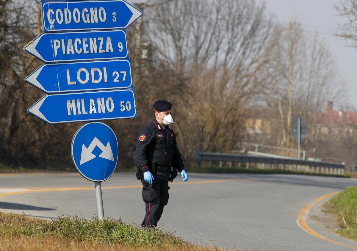 An Italian officer helps monitor traffic southeast of Milan, where the coronavirus has infected hundreds. A doctor traveling from Italy to the Canary Islands tested positive for the virus.