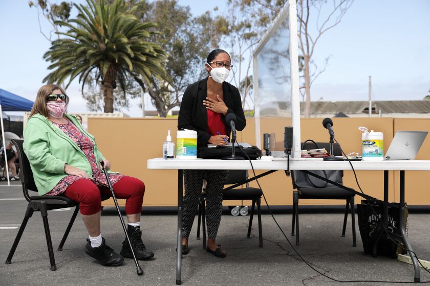 REDONDO BEACH-CA-MAY 26, 2021: Deputy public defender Mercedes Cook, center, speaks on behalf of Michelle Scott, 54, left, at homeless court, held in a parking lot at the Redondo Beach Police Department's Investigations Division on Wednesday, May 26, 2021. (Christina House / Los Angeles Times)