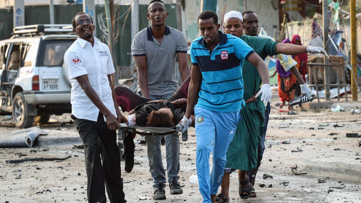 Somalis carry a wounded person after the car bomb attack Friday in Mogadishu.